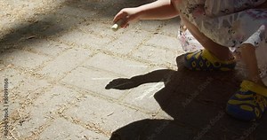 Anonymous girl draw with crayons on the ground in the Park