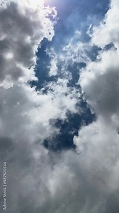 cumulus clouds move across a deep blue sky as the sun rays filter through