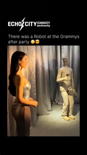 EchoCity on Instagram: "The Grammy After-Party Robot This video features a surreal encounter at a high-profile industry event. Standing among celebrities in high-fashion attire is a sleek, white humanoid robot. The robot isn't just a statue; it’s seen holding a smartphone, mimicking the behavior of the influencers around it. The robot is actually "Ameca," developed by Engineered Arts, known for its incredibly lifelike facial expressions and fluid movements. The video went viral because it blurre