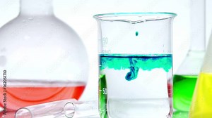 Different types of chemical laboratory glassware with liquids inside: a subject video recording on a white background. Round bulb, beaker and test tube. Color experiments.