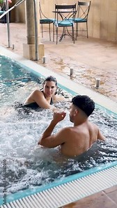 Vertical video of a Caucasian couple in their 20s and 30s having fun in the spa of a luxury hotel. The couple talks in a pool with bubbles. Newlywed couples concept.