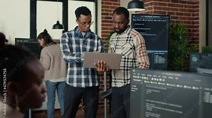 Software programmers talking about algorithms holding laptop switching focus on cloud programer writing code typing. Team of coders discussing artificial intelligence in programming office.