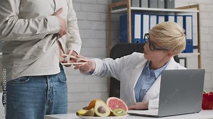 Female doctor nutritionist measuring male patient fat index with caliper, discussing dieting during personal appointment