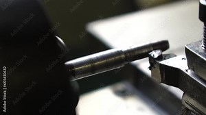 Close-up lathe machine operation by cutting the metal tube. vintage lathe machine tool operates with metal detail under mature worker control in old production plant workshop. Slow motion