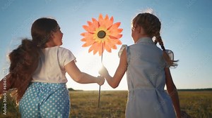 child girls running with windmill a toy lifestyle in the park. happy family kid dream concept. daughters girls playing with toy windmill in nature. childhood freedom wind concept outdoors lifestyle