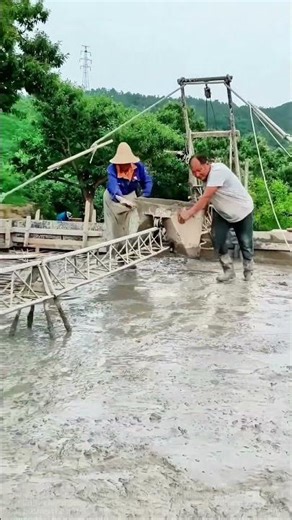 Rural workers show how to operate a manual concrete mixer in muddy conditions!