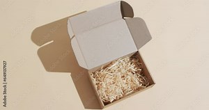 Video of opened cardboard box with paper shavings and copy space over brown background