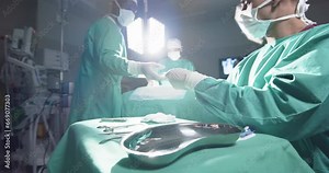 Diverse surgeons using surgical instruments in operating theatre at hospital, slow motion