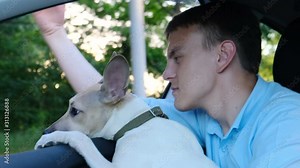 Cheerful owner with a dog riding in a car leaning out the window, slow motion