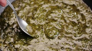 Cooking green pesto sauce close-up. Italian Pesto is a sauce that traditionally consists of crushed garlic, European pine nuts, coarse salt, basil leaves, and hard cheese such as Parmigiano