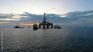 Aerial view from a drone of an offshore jack up rig at the offshore location during evening. Oil rig drilling platform in the sea.