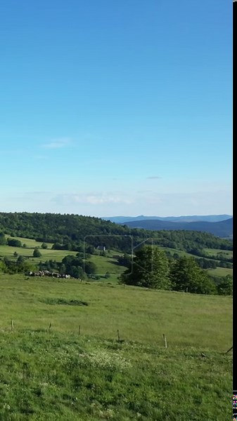Scenic view of green rolling hills and open fields under a clear blue sky in the Ardeche countryside, France. Lush vegetation and distant forests create a peaceful rural landscape Stock Video Footage - Alamy