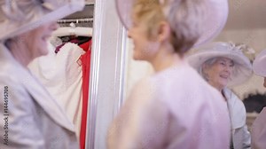 2 Mature ladies drinking champagne and trying on clothing for a special event
