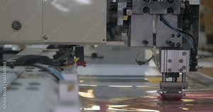 In an industrial garment factory, an automatic sewing machine sews various strips on fabric offline. Concept of: Automatic sewing machine, Work, Cloth, Textile.