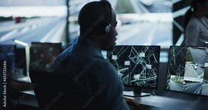 Multicultural Surveillance Specialists Work in a Dimly Lit Monitoring Room. Officers Track Target from Satellite on Computers. High-Tech Environment with Cybersecurity and Military Operations
