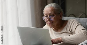 Focused older adult female pensioner learn how to use modern laptop pc study app with user friendly interface work online. Aged lady read email from computer screen check new messages at mail client