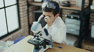 Adorable hispanic boy student using microscope at laboratory classroom