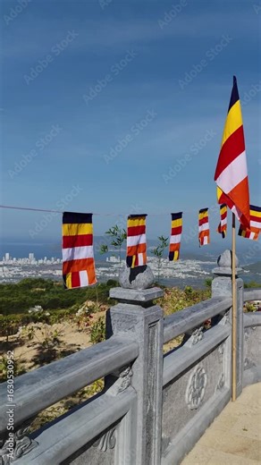 Buddhist flags wave in wind as Nha Trang city stretches out below the mountain.