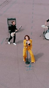 Vertical. Sexy girl sings cool in a band. Music band played against stadium background. Beautiful female singer sings in the city center. A model in a bra sings in a band.