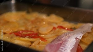 Cooking raw hake fish in oven with paprika, sesame oil, potatoes, onions, garlic and red bell pepper. French restaurant.Cooking Health Concept Home. Professional closeup. Dinner gourmet. Gastronomy