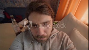 Alcoholic hangover problem. Alcoholic man with an alcohol addiction problem waking up in the afternoon after drunken binge, gets up hard with a bad hangover. Suffering from the effects of alcohol