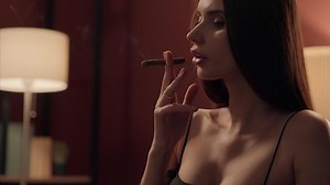 Stylish sensual addict relaxed Caucasian woman female girl gambler lady in dress smoking cigar blowing out puffs smoke cigarette enjoying relax at home night weekend party casino. Bad habit addiction
