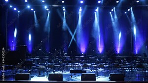 Concert light. Stage lighting background. An empty stage and a hall without people. There are a lot of empty chairs and microphones on the stage for musicians.