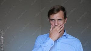 4k. Close up. Portrait of a young man. sign language and gestures. he covers his mouth with his hand and keeps silent