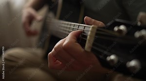 Capturing hands expertly strumming and fingering chords on an acoustic guitar's fretboard, showcasing musical talent and intricate finger movements