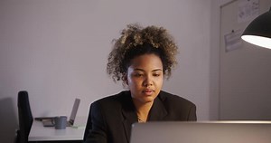 A woman in a business suit sitting at a desk with a laptop