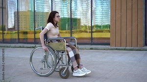 Young woman in a wheelchair. A girl rides in a wheelchair against the background of a glass building. Special transport for the disabled.
