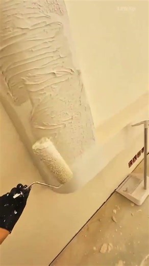 dipping paint roller into a bucket of white plaster and applying it to wall to create textured finis