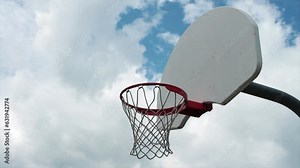 outdoor basketball net with white backboard and mesh screen right with silver post protruding from its back, clouds in background