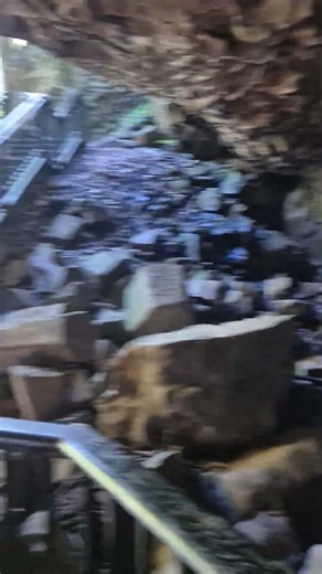 A wooden staircase leading to a waterfall in a cave