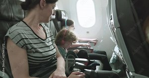 Woman and two children sit on a plane on a bumpy ride as the plane taxis across the tarmac to the terminal after landing