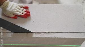 Builder using a hacksaw cuts aerated concrete block. Construction contractor cuts autoclaved aerated concrete block, aerated concrete with a hand saw at a construction site. A construction worker saws