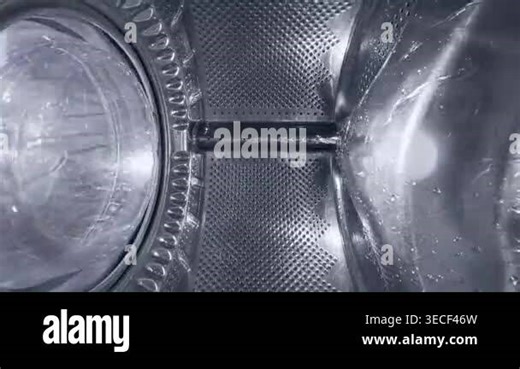 Creative wide-angle view from inside a spinning washing machine drum. Water streams down the metallic surface during a wash cycle. Industrial and domestic cleaning concept Stock Video Footage - Alamy