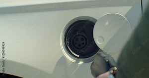 Man plugging in electric car at home at electro charging station. Luxury white electrical car recharging. Environmentally conscious man charging his electric vehicle. Stock Video