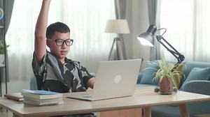 Teenage Boy Learning Online From Laptop, Raising Hand Distance Learning Online At Virtual Lesson Class With Teacher Tutor On Laptop By Video Conference