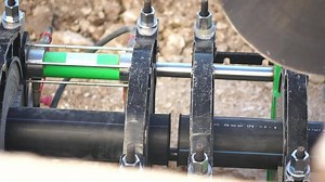 Welding plastic pipe. Workers with professional equipment for high-quality gluing pieces of plastic pipe in a single pipeline. Slow motion. Close up