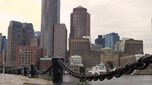 Boston skyline from Harborwalk Fan Pier Park in slow motion on a cool fall day by the water with chains in foreground