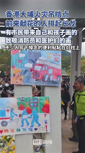 香港大埔火災吊唁點，前來獻花的人排起長龍，有市民帶來自己和孩子畫的致敬消防員和醫護們的畫，不少人寫下悼念的便利貼粘在燈柱上