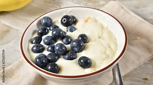 Stop motion animation of a bowl of yogurt being topped with blueberries and almonds
