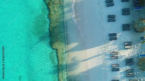 Drone top down rising above Grote Knip beach Curacao above reclining beach chairs, long shadows