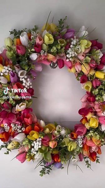 Bring the beauty of a blooming spring garden right to your front door with this lush, colorful grapevine tulip wreath, handcrafted with love and attention to every detail. This stunning wreath is filled with vibrant tulips in shades of pink, coral, yellow, cream, peach and soft lavender, creating a joyful wildflower-inspired design that feels fresh, cheerful, and full of life. Delicate baby’s breath and soft greenery are layered throughout, adding texture, movement, and an airy elegance that ele