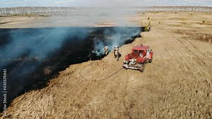 Burning dry grassGrass is burning in meadow. Ecological catastrophy. Fire and smoke destroy all life. Firefighters extinguish Big fire. Lot of smoke. Climate change, ecology, earth