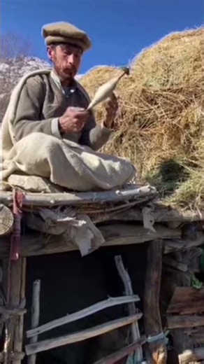 A man is preparing wool yarn with the help if an ancient spindle the oldest way of spinning