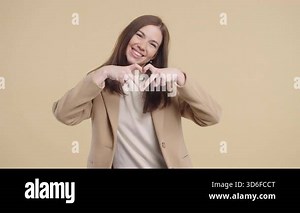 Smiling pretty woman showing sign of shape heart. Positive lady on beige. Love. Lady health, volunteering, charity donation, gratitude symbol, flirting concept. High quality 4k footage