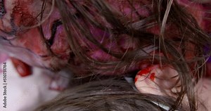 Hungry spooky man bites and eats piece of neck from victim. Zombie with mustache and blood spots on body kills and eats young woman extreme closeup