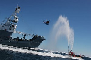 Greenpeace ship, boats and helicopter hinder a whaling ship.